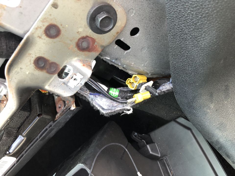 Yellow FAKRA connectors and black wiring behind dash near rusty metal bracket in vehicle interior