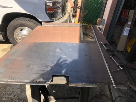 1992 Jeep Wrangler - A metal plate with cutouts and markings is clamped to a workbench, with a vehicle's front end visible in the background.