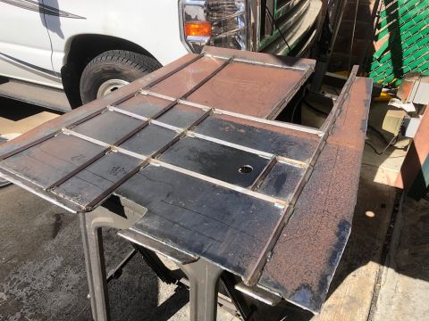 1992 Jeep Wrangler - Custom metal panels are being worked on, with a portion of a white truck visible behind them.