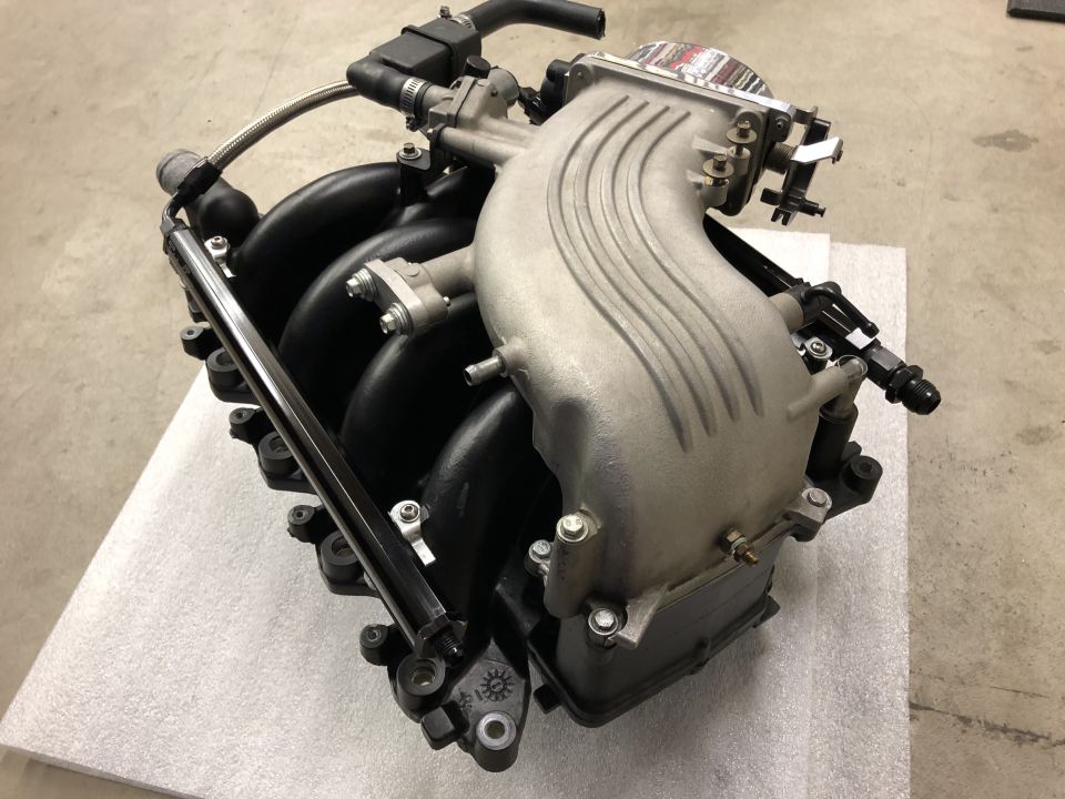 Aluminum intake manifold assembly with fuel rail and injectors on a workshop floor