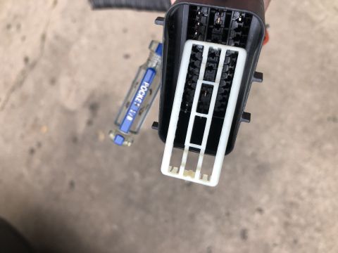 2015 Ford Explorer - A close-up view of an automotive electrical connector and a small screwdriver.
