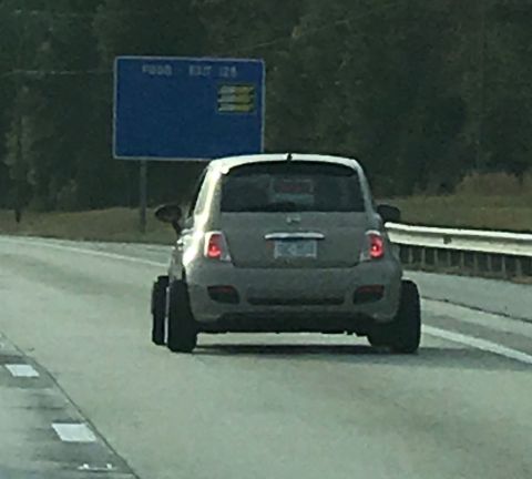 2009 Harley-Davidson FLH - A gray hatchback car is seen from behind on a highway with a blue road sign in the background.