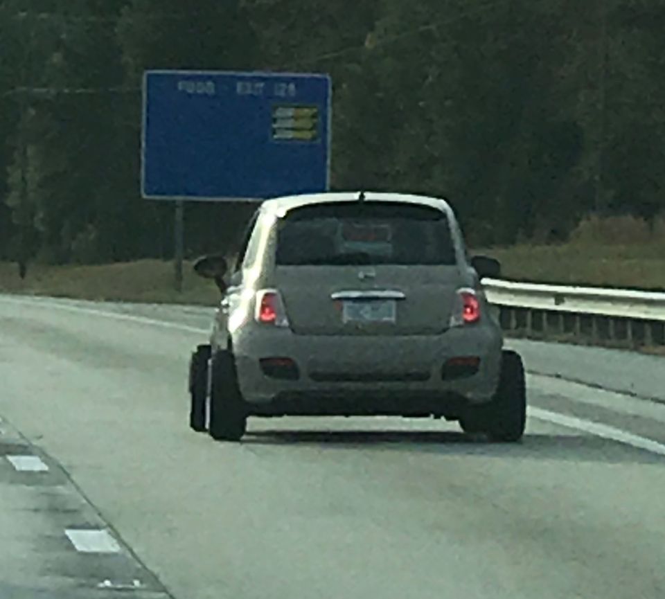Gray hatchback car with wide rear tires on a highway