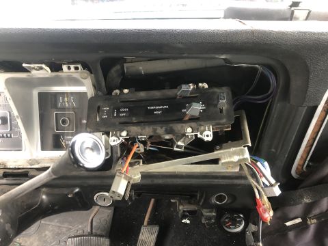 1979 Ford Bronco - The interior of a vehicle shows a disassembled dashboard with exposed wires and climate control components.