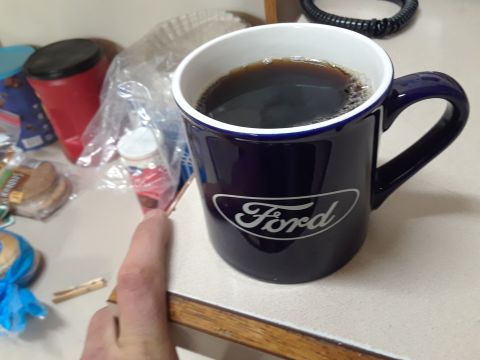 1994 Ford Bronco - A dark blue coffee mug with the Ford logo is on a counter next to some food items.