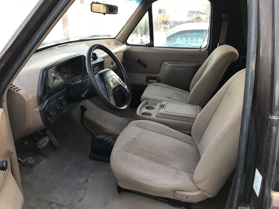 Brown cloth seats and dashboard of a 1987 Ford Bronco, viewed from passenger side