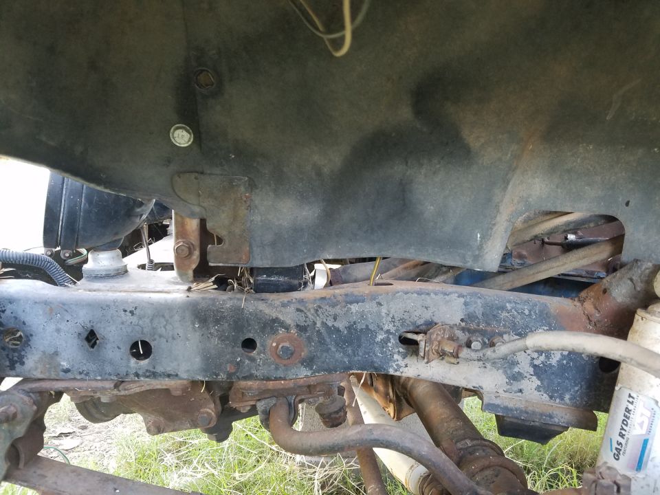 Underside of a Jeep showing frame, suspension components, and part of the engine bay