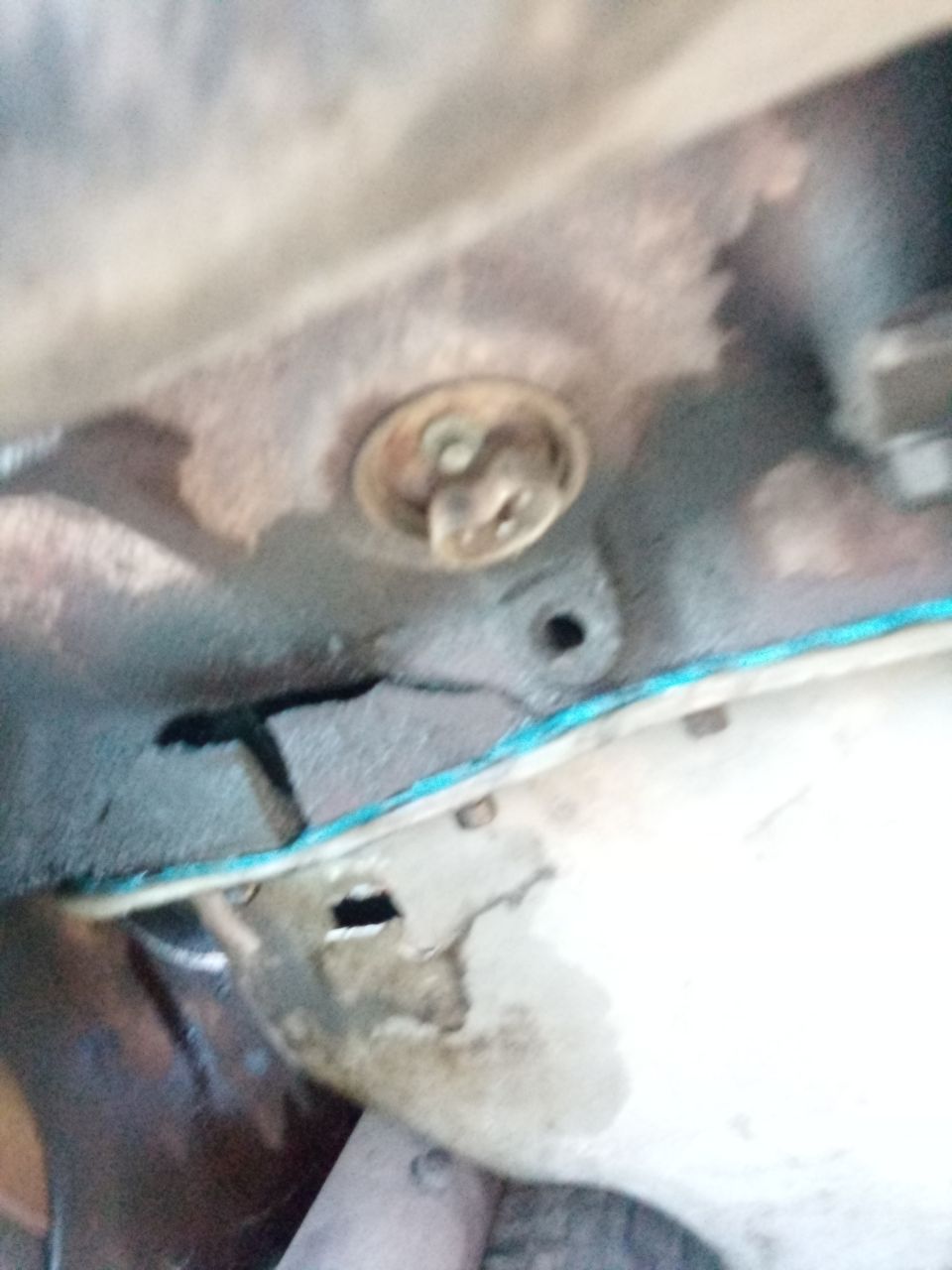 Close-up of a metal engine component with some blue gasket material visible