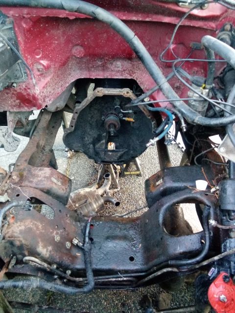 1994 Ford Bronco - The transmission bell housing is visible, supported by jack stands, with the vehicle's frame in the foreground.