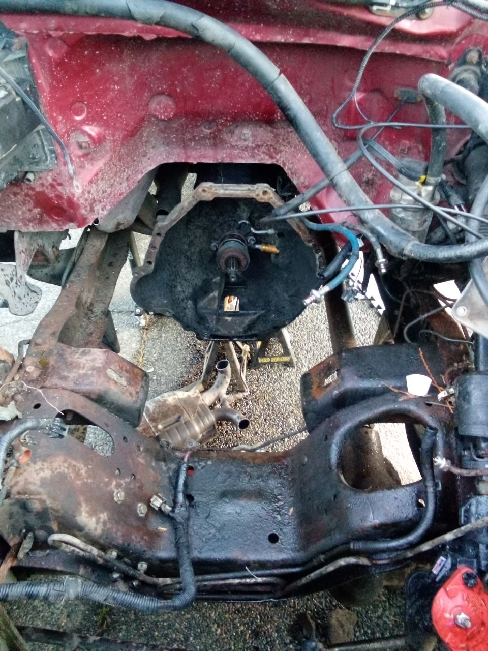 Transmission bell housing and rusty frame of a red vehicle