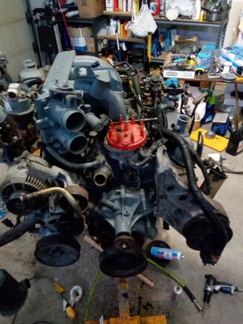 1994 Ford Bronco - An engine assembly, likely out of a vehicle, is shown with its various components including a red distributor cap and blue intake manifold.
