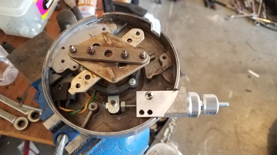 Close-up of a vehicle distributor assembly held in a vise, showing internal mechanical components and wiring
