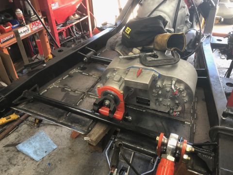 1992 Jeep Wrangler - The transmission and frame of a vehicle are shown in a workshop setting, with various tools and equipment present.