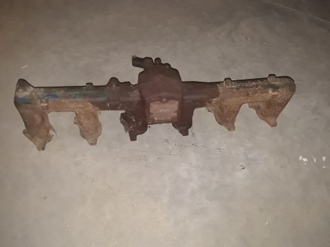 1994 Ford Bronco - A rusty exhaust manifold is shown on a concrete surface.