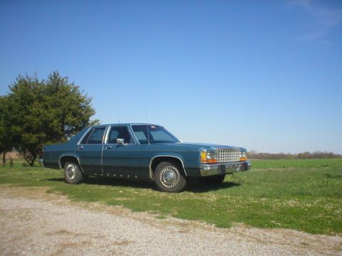 1987 Ford Crown Victoria LTD - A teal 1987 Ford Crown Victoria sits parked on a gravel shoulder under a clear blue sky.