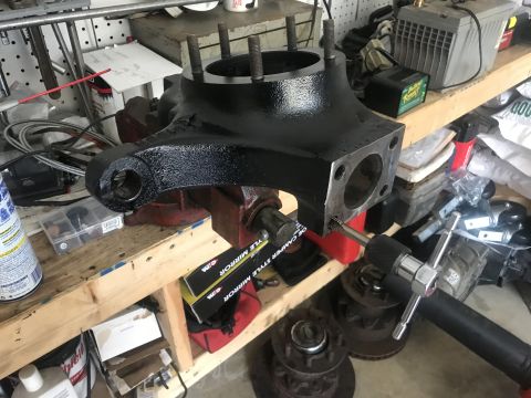 1989 Ford Bronco - A vehicle axle housing assembly is being worked on in a garage setting.