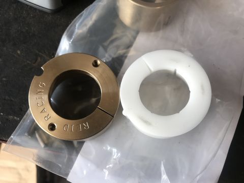1989 Ford Bronco - Two bearing collars, one brass and one white plastic, are shown on a table.