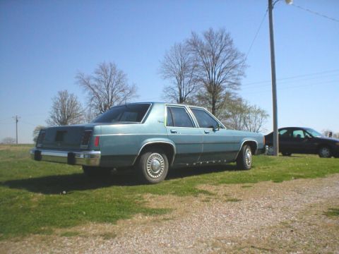 1987 Ford Crown Victoria LTD - A light blue 1987 Ford Crown Victoria LTD sedan is parked outdoors with another vehicle in the background.