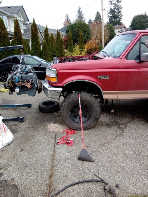1994 Ford Bronco - A red 1994 Ford Bronco is shown with its engine being removed by a hoist.