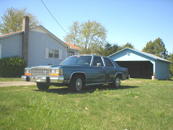 1987 Ford Crown Victoria LTD parked in front of a blue garage