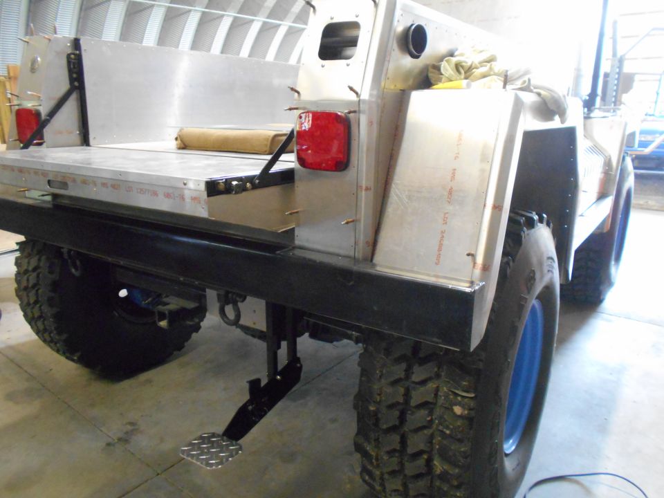Rear view of custom aluminum truck bed with red taillight and diamond plate step