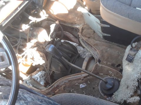 1994 Ford Bronco - The interior of this vehicle shows significant rust and wear around the transmission tunnel and floor area.