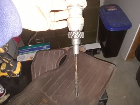 1994 Ford Bronco - A distributor part is held over a car floor mat, with other items visible in the background.