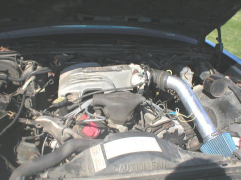 1987 Ford Crown Victoria LTD - The engine bay of a 1987 Ford Crown Victoria LTD, an aftermarket air intake system and visible 'CAUTION FAN' text.