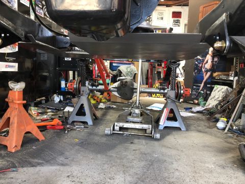 1992 Jeep Wrangler - The underside of a vehicle is supported by jack stands in a workshop setting.