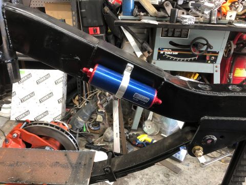 1992 Jeep Wrangler - Close-up of a fuel filter installed on a vehicle's frame in a workshop setting.
