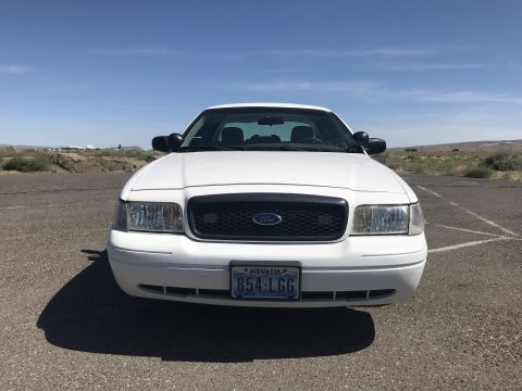 1987 Ford Bronco II - A white Ford Crown Victoria is parked outdoors under a clear blue sky, showing its front grille and Nevada license plate.