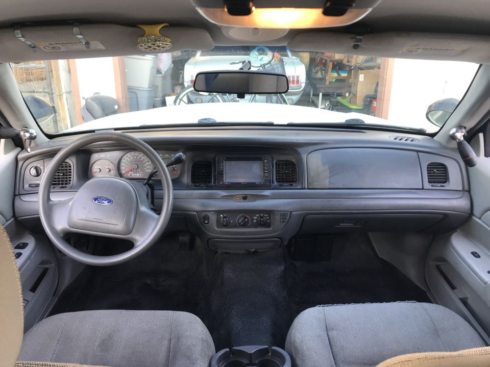 Car interior dashboard with Ford steering wheel, radio, and gray seats