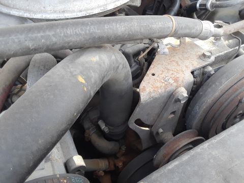 1994 Ford Bronco - Close-up view of engine components, including hoses and a pulley system.
