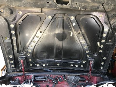 2000 Ford Explorer - The underside of a car's hood is shown, revealing the hood's structure and some engine components beneath.