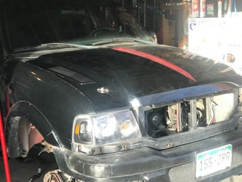2000 Ford Explorer - Front view of a black Ford Ranger truck undergoing repairs in a garage.