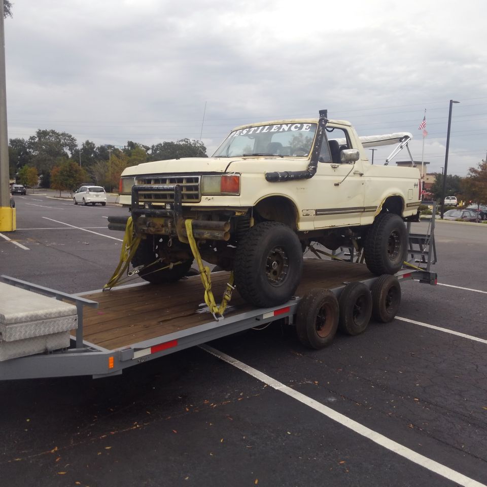 Cream lifted pickup truck with snorkel and "DESTILENCE" on windshield, on a trailer