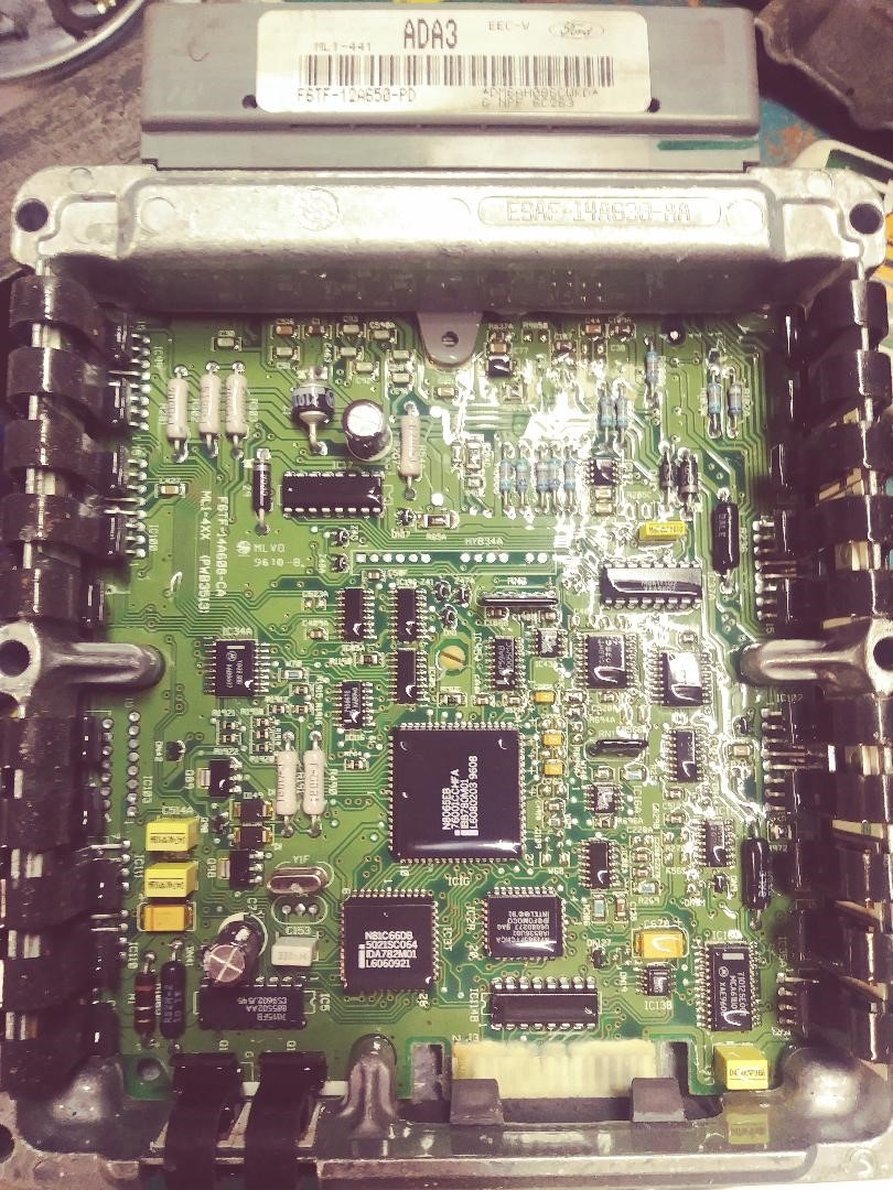 Engine control unit circuit board with visible chips and components. Label reads ADA3