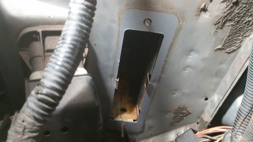 Engine bay with corrugated hose and metal bracket with rectangular opening. Some rust visible