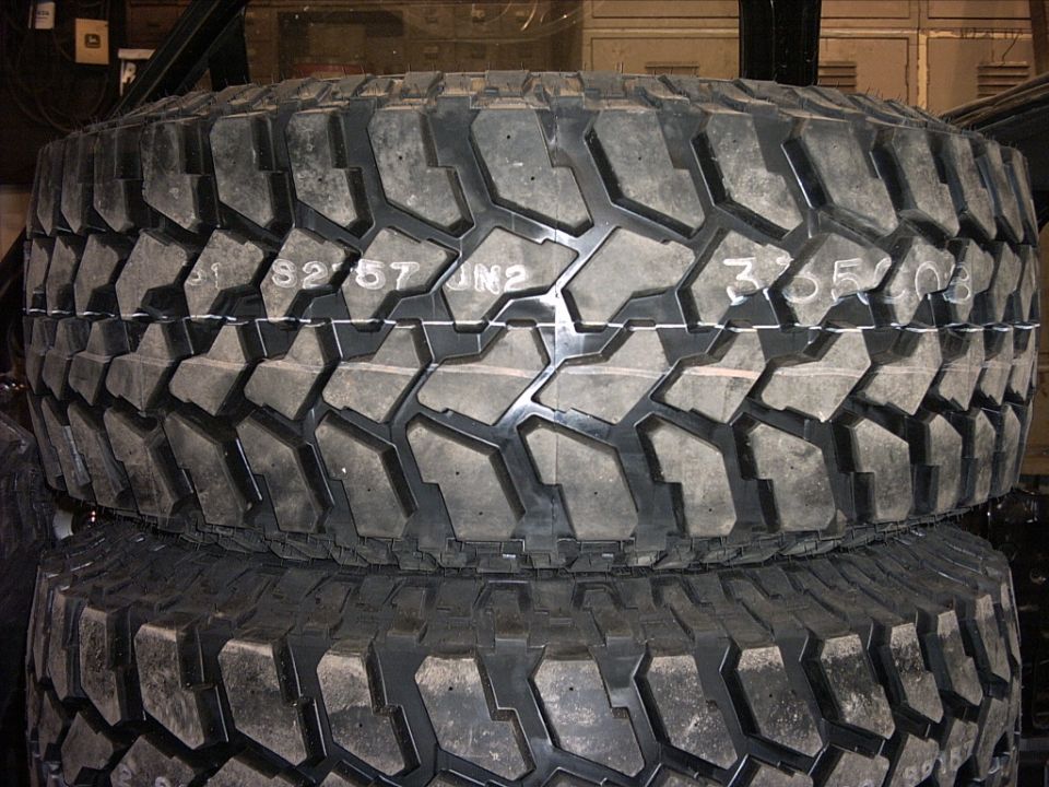 Stacked off-road tires showing aggressive tread and white sidewall markings