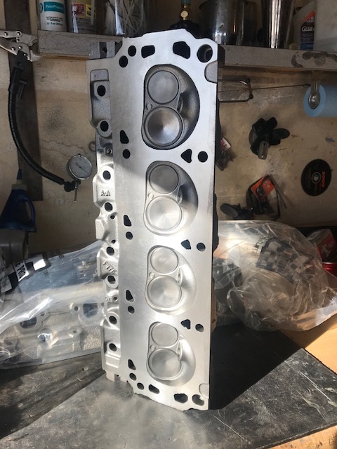 2000 Ford Explorer - An engine cylinder head sits on a workbench, showing its internal valve chambers and bolt holes.