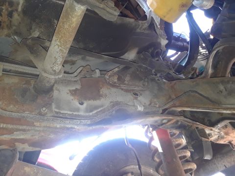 1994 Ford Bronco - The undercarriage of a vehicle shows significant rust and wear on its frame and suspension parts.