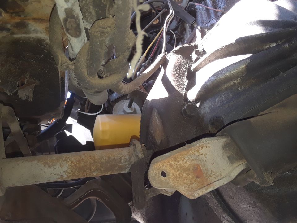 Close-up of an engine oil filter and rusty metal suspension parts