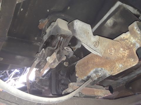 1994 Ford Bronco - Close-up of rusted vehicle undercarriage parts, showing suspension and frame elements.