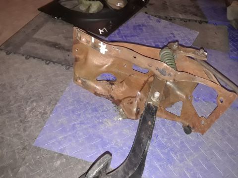 1994 Ford Bronco - A rusty metal bracket assembly with a spring and pedal is shown on a tiled surface.