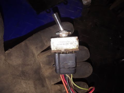 1994 Ford Bronco - A toggle switch with a part number visible is held by a gloved hand, with wiring attached.