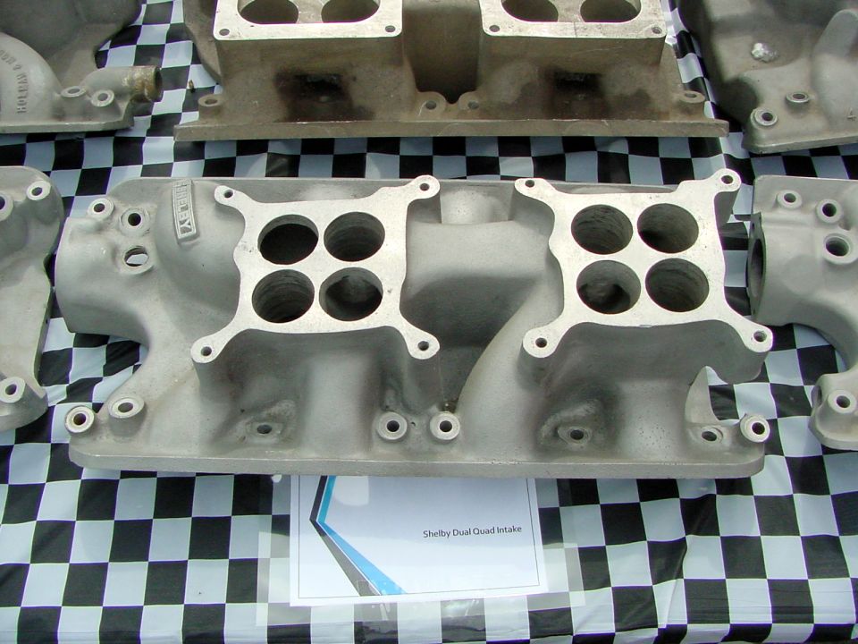 Aluminum Shelby dual quad intake manifolds displayed on checkered cloth