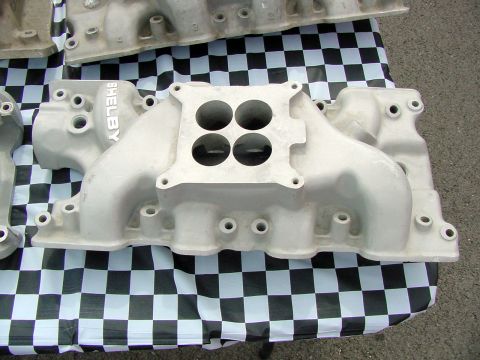 1969 Ford Mustang - A Shelby intake manifold is displayed on a checkered tablecloth, with other manifolds visible in the background.