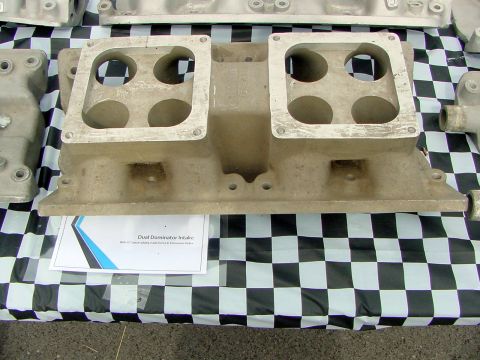 1969 Ford Mustang - A close-up of an aluminum intake manifold with four carburetor mounting holes is displayed on a checkered cloth.