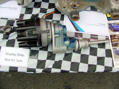1969 Ford Mustang - Close-up of an automotive distributor and part of an intake manifold displayed on a checkered cloth.