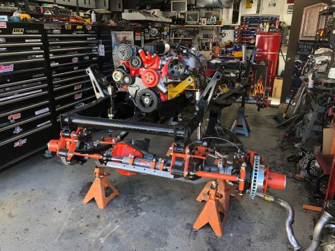 1992 Jeep Wrangler - Jeep chassis and engine assembly on stands in a workshop. SuperMotors logo in corner.